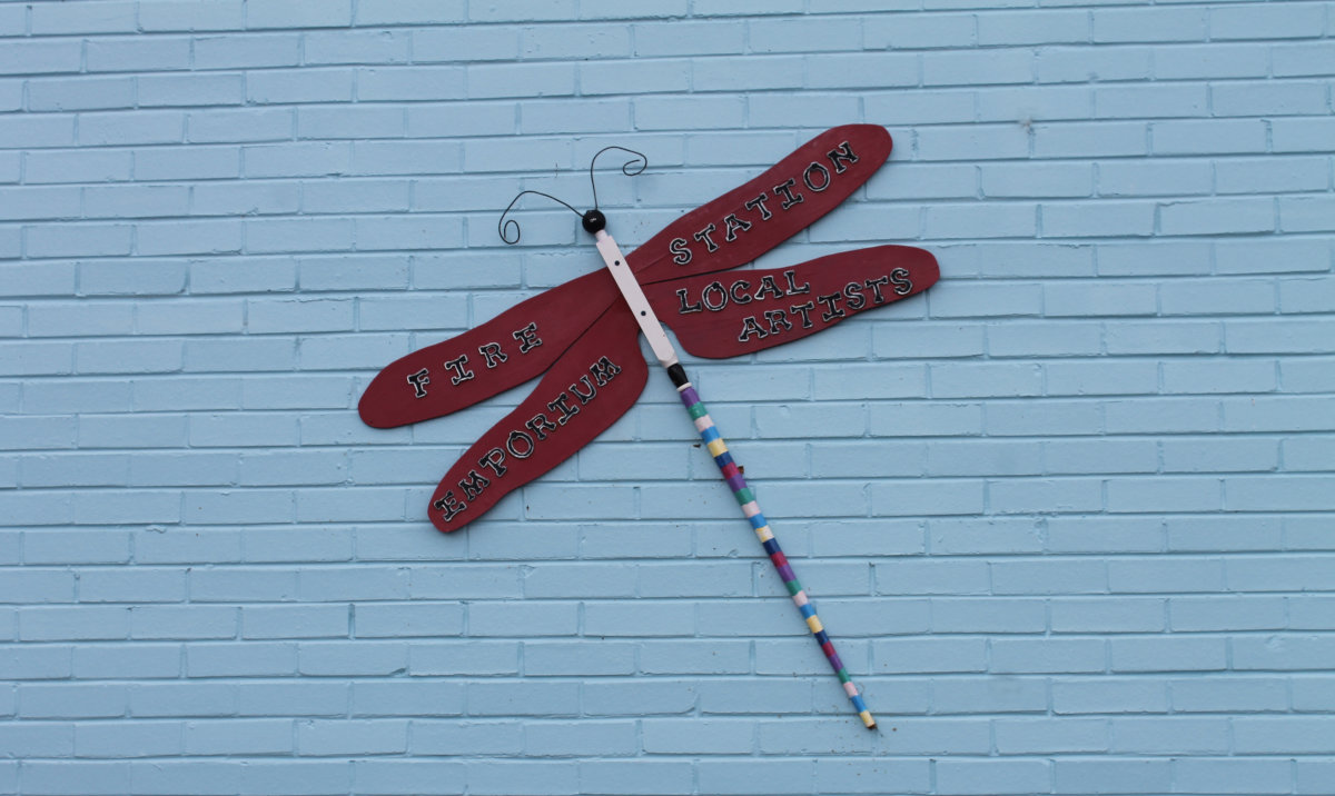 Wooden dragonfly art piece with wings reading Fire Station, Local Artists, Emporium
